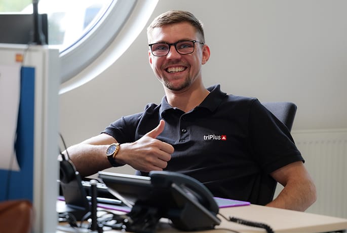 Mitarbeiter der triPlus Systemhaus GmbH am Arbeitsplatz in einer freundlichen, modernen Büroumgebung.